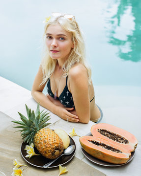 Beautiful girl in pool eating fruits