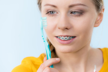 Woman smiling cleaning teeth with braces