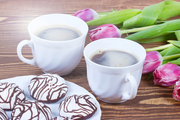 Breakfast for Valentines day with two cups of coffee, flowers and cake.