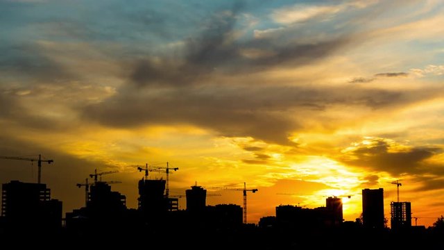 Construction site including few cranes working on a building complex with blurred natural background sunset pastel. Construction crews work on high ground heavy industry and safety concept. Zoom-in.