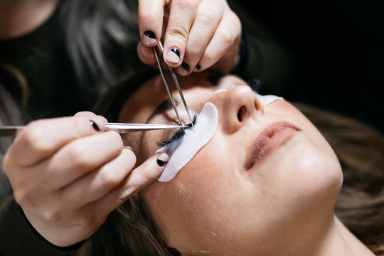 Young woman getting lash extension cosmetology laying down in small business studio