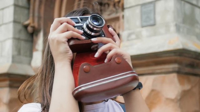 Slow motion video of beuatiful smiling tourist girl making photographs of city on old fil camera