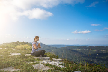 Naklejka na ściany i meble Young woman relax and meditate alone at top of mountain in warm summer day, healthy lifestyle