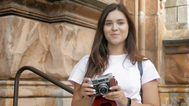 Slow motion footage of smiling tourist girl with long dark hair looking in camera and making photographs