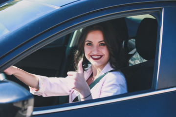 Woman driving car and gesturing thumb up