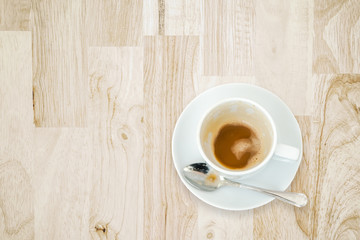 leftover coffee in white ceramic cup with spoon on wooden desk , top view