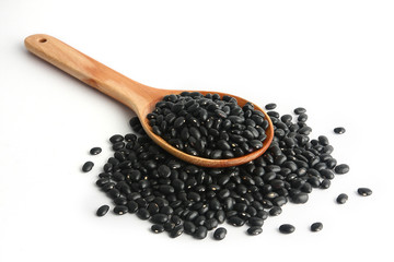 Black beans are in a wooden spoon.