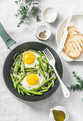 Healthy breakfast or snack - a fried egg with green beans in the pan on a light background, top view