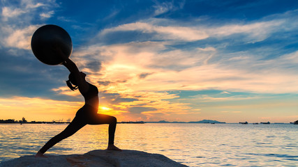 Yoga ball, pilates ball young woman in the sunrise background. Healthy Concept.