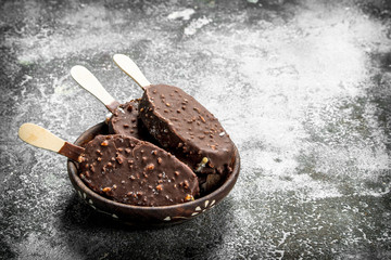 Fresh ice cream on a stick in chocolate with nuts.
