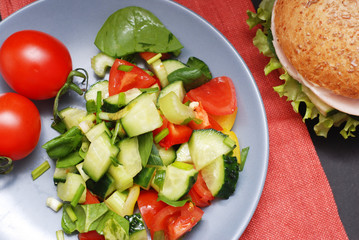 Salad of Cucumbers, Tomatoes and Greens on a plate, Top view. Diet and Health Concept. Food.