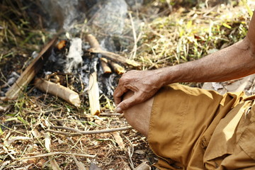 Buddhist monk sitting by a smoking fire