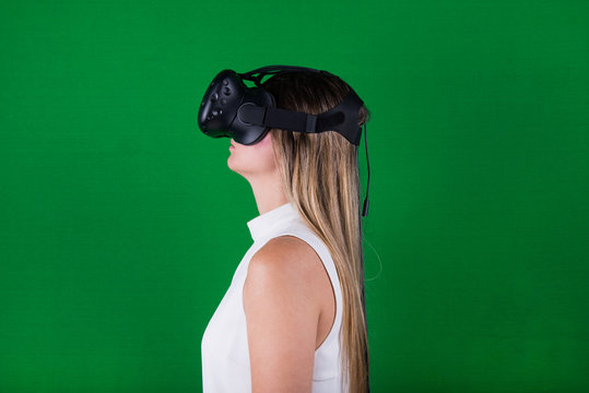 attractive woman wearing virtual reality headset in green screen studio