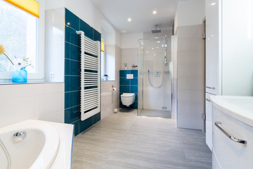 Spacious bathroom in blue and white tones with heated floors, walk-in shower, sink vanity and skylights
