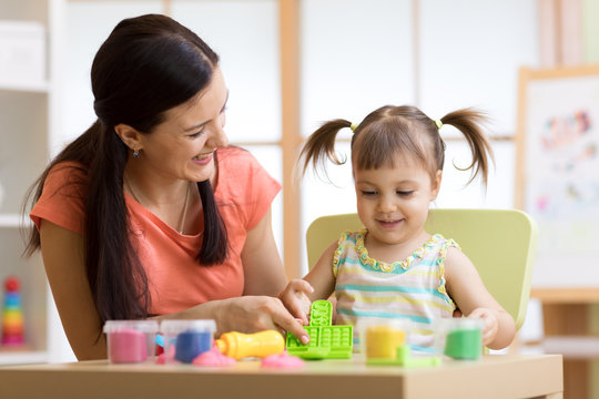 child kid girl and mother play colorful clay toy at nursery or kindergarten