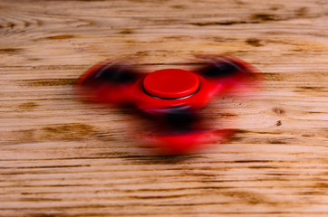 Red fidget spinner rotates on wooden desk