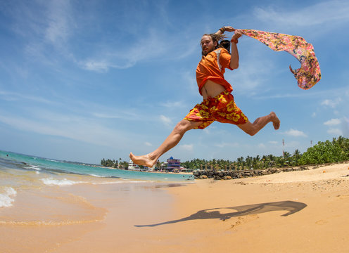 Beautiful man running and jumping in the beach with a colored tisue