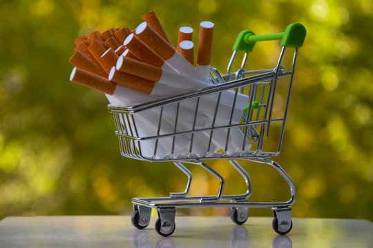 A small shopping trolley with cigarettes on a green background