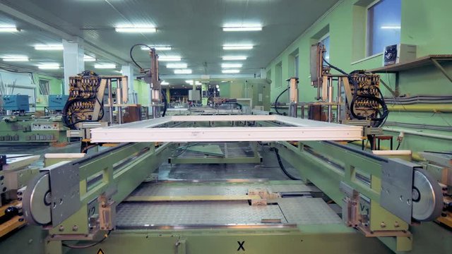 An assembled window frame moves away on a conveyor line. 