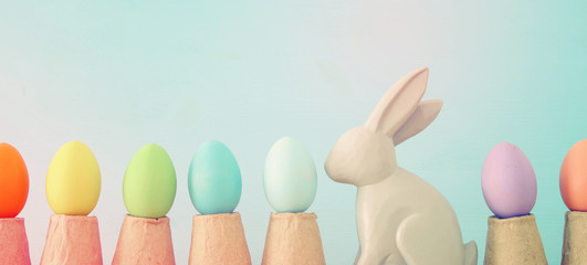 Cute bunny next to easter colorful eggs over colorful background.