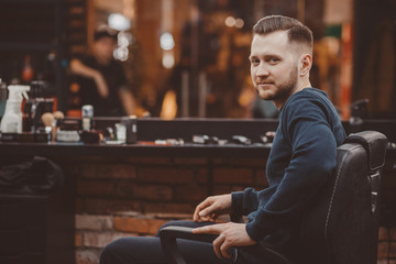 Barbershop. man with a beard and hairdo in a male hairdresser sits in a chair