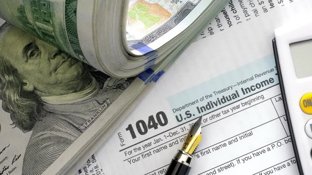 USA tax form 1040 and dollar bills, close up. High angle view.
