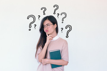 Young asian Student woman holding book and question marks doodles at the back ground with copy space