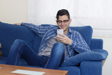 young man with mobile phone on the sofa in the apartment