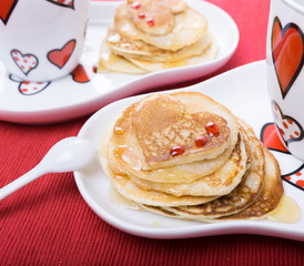 Festive dish-Valentines day homemade heart shaped pancakes on a red napkin, tea, coffee