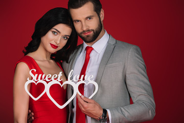 attractive couple holding sign sweet love isolated on red