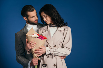 boyfriend presenting bouquet to girlfriend isolated on blue