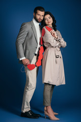 couple holding garland of red hearts and looking at camera on blue