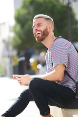 male college student smiling outside with mobile phone