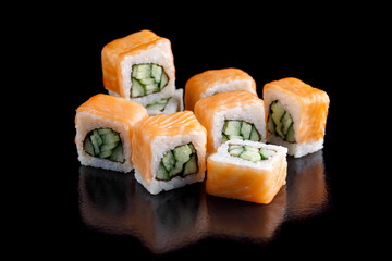 Original set of sushi with salmon and cucumber on a black background close-up.