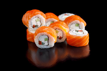 Original set of sushi with salmon and Philadelphia cheese on a black background close-up.