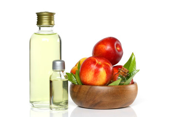 Peach natural organic oil. Peach oil in a glass bottle and ripe peaches in a wooden cup. 
