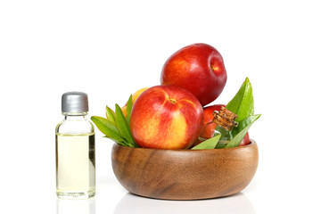 Peach natural organic oil. Peach oil in a  bottle and ripe peaches in a wooden cup. 