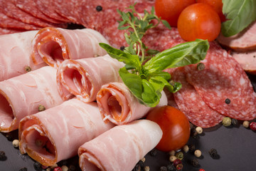 meat assortment of sausage, bacon, prosciutto decorated with basil leaves