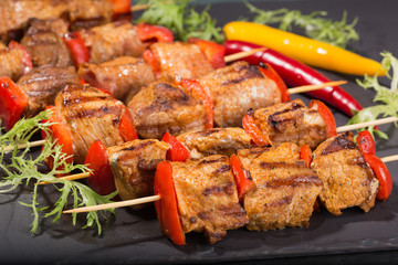 shish kebab from meat on a black slate, sticks of pepper and spices