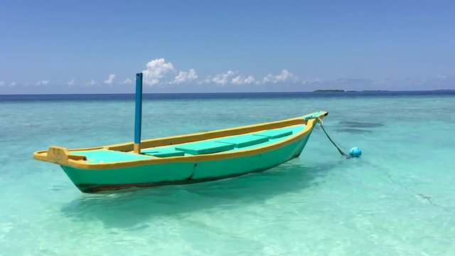 Small colourful boat docked near a tropical beach