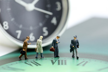 Miniature people : business man looking at watch and walk on the clock background, time business...