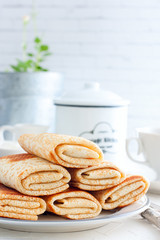 Fototapeta na wymiar Stuffed pancakes on a white plate, selective focus