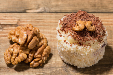 cake on a wooden table, dessert decorated with walnut, walnut nearby, rustic style