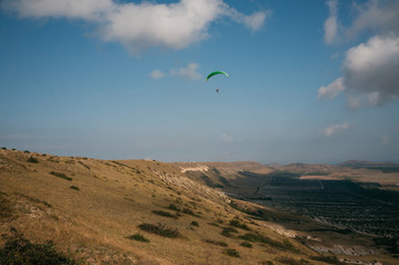 Parachutist gliding in blue sky over scenic landscape of Crimea, Ukraine, May 2013