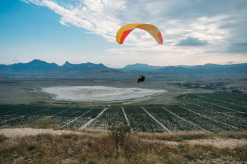 Parachutist gliding in blue sky over scenic landscape of Crimea, Ukraine, May 2013