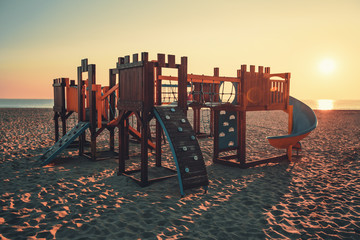 Wooden playground for small children on the beach in sunny morning. Sea sunrise.