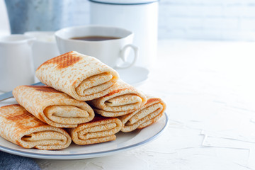 Homemade pancakes stuffed, wrapped with an envelope on a white plate, traditional food on a pancake week, horizontal, copy space