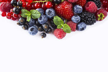 Ripe blueberries, red currants, raspberries, strawberries with mint on a white background. Mixed berries with copy space for text. Black-blue and red berries and fruits. Top view.