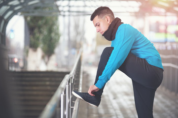 Fototapeta na wymiar Male runner or fitness man preparing for jogging. Young handsome man exercising outdoors in winter urban location