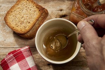 tazza di the caldo pronta con cucchiaino fette biscottate e marmellata